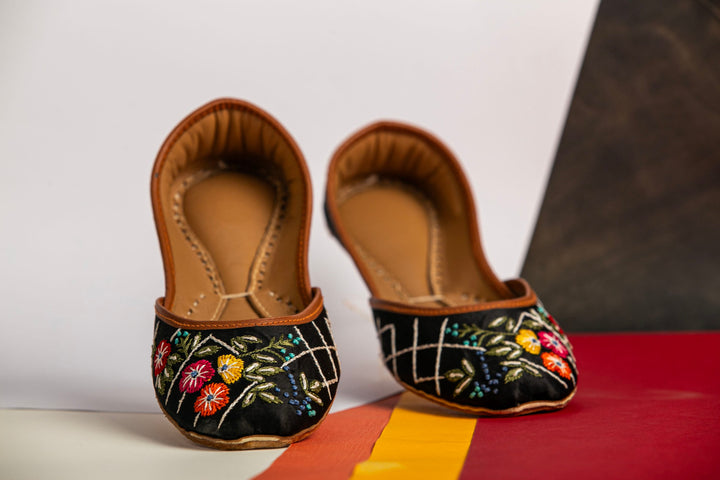 Black Indian jutti with red, yellow and orange flower embroidery.