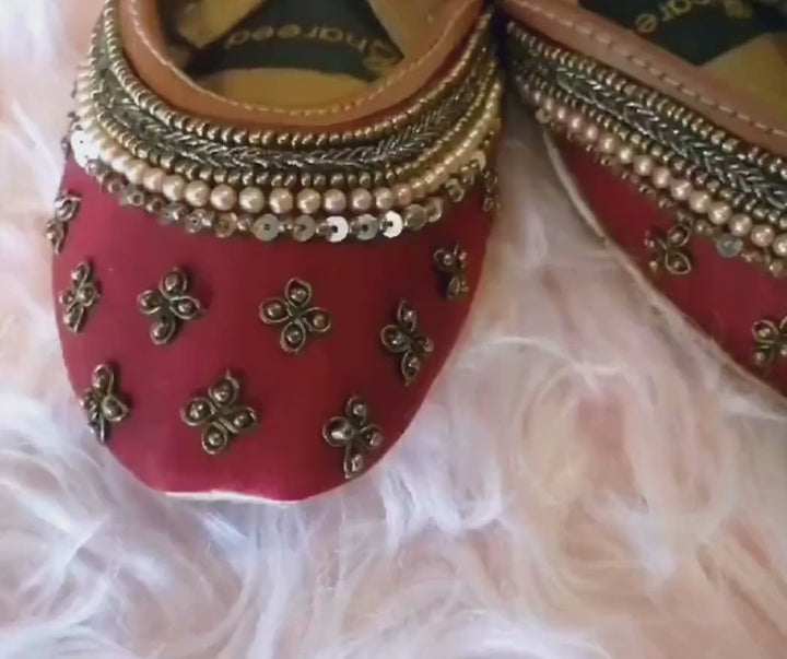 Close-up video of Bridal Pearl maroon satin wedding flats with gold-tone floral motifs and pearl and sequin trim.