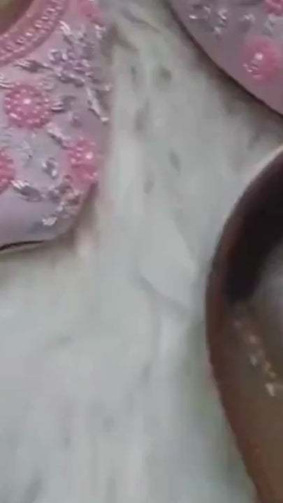 Close-up video of powder pink satin bridal flats with pink floral beadwork, silver embroidery, rhinestones and tan stitched insoles.